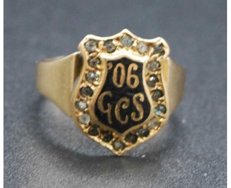 A 19th century yellow metal, black enamel and white sapphire set mourning ring, having a shield shaped plaque with white sapp