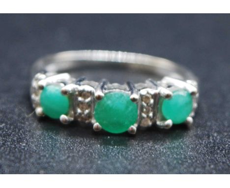 A 14ct white gold, emerald and diamond half hoop eternity ring, featuring three graduated round faceted emeralds alternating 