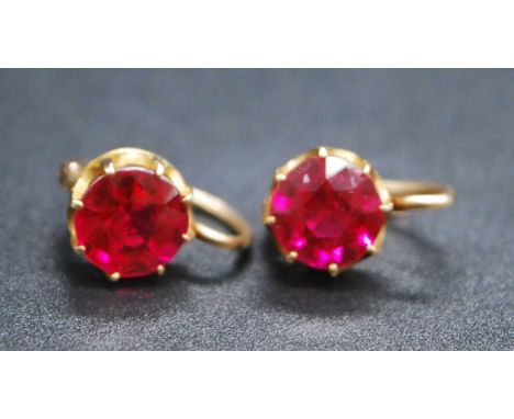 A pair of yellow metal synthetic ruby drop earrings, each with a round faceted ruby in a claw setting, with hinged hook fitti