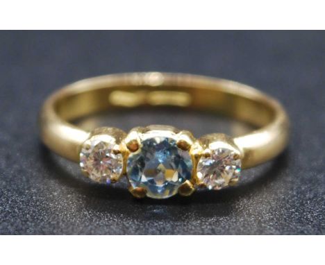 A yellow metal, aquamarine and diamond three stone ring, featuring a centre round faceted aquamarine with a round brilliant c