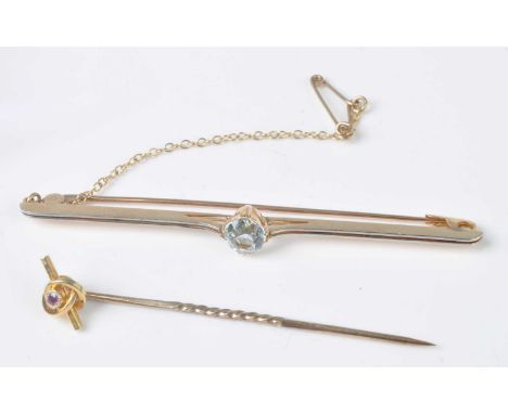 A yellow metal aquamarine bar brooch, featuring a centre round faceted aquamarine in a four double claw setting, with hook st