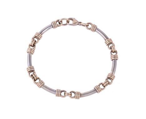 
	
		A 9 CARAT GOLD TWO COLOUR BRACELET
		The slightly bowed white coloured bars with reeded gold coloured caps, to a lobster