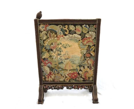 VICTORIAN WOOLWORK FIRE SCREEN
with a pair of finials above a panel decorated with a lady holding some flowers in a garden, w