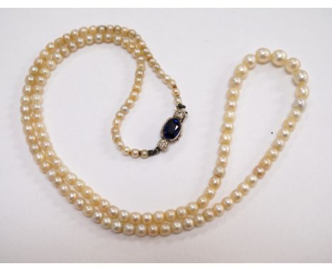 GRADUATED PEARL NECKLACE
with sapphire and diamond set unmarked gold clasp, the oval cut sapphire approximately 0.75cts flank