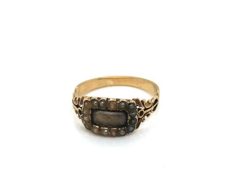 An antique memorial ring with a glazed hairwork panel surrounded by a cluster of seed pearls. Unhallmarked, assessed as 13ct 