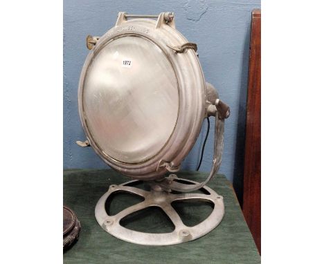 A Crouse Hinds search light, the grey metal casing rotatable on a wheel shaped foot