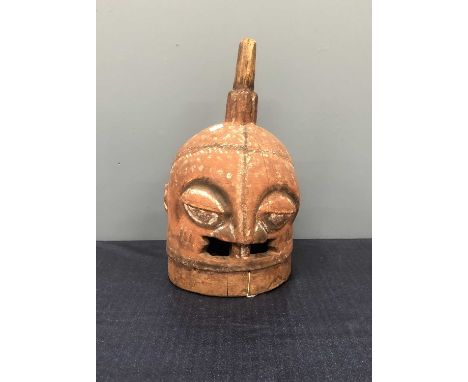 A Yoruba gelede wooden helmet mask, the stylised head decorated with black bands and stippled in white on a red ground.   H 4