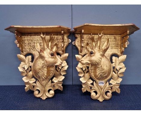 A pair of gilt wood wall brackets with deer's heads below the shelf tops, the back board based by pierced foliage
