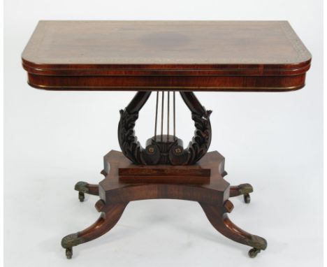 A REGENCY ROSEWOOD AND BRASS INLAID PEDESTAL CARD TABLE, THE ROUNDED OBLONG TOP WITH FOLIATE SCROLL BORDER AND RED BAIZE LINE