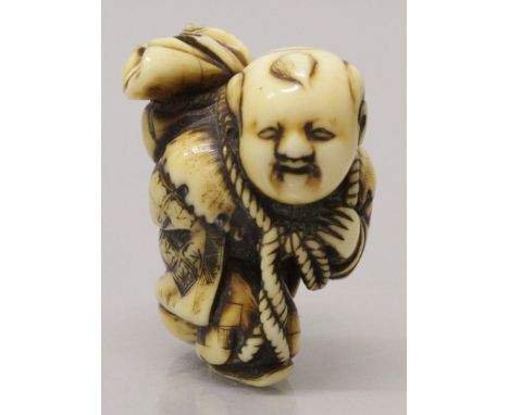 A GOOD SIGNED EARLY 19TH CENTURY JAPANESE EDO PERIOD CARVED IVORY NETSUKE OF A BOY, walking and carrying a rope bound bag on 