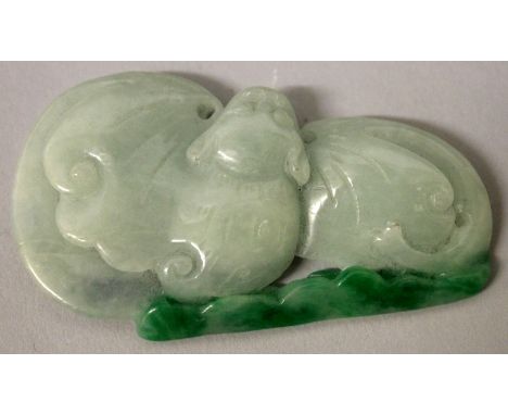 A CHINESE CELADON JADE-LIKE PENDANT OF A BAT, its wings open beneath apple-green cloud scrolls, 2.5in x 1.3in at widest point