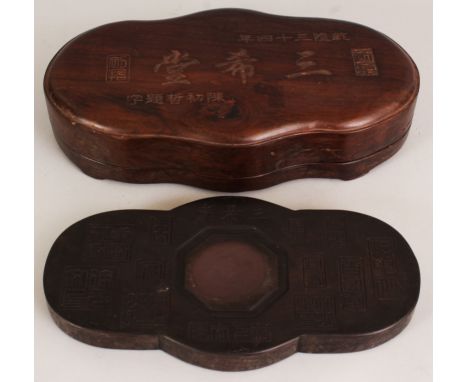 A SHAPED CHINESE BLACK INKSTONE, in a fitted wood box and cover, the cover and inkstone with calligraphy and seals, the box 1