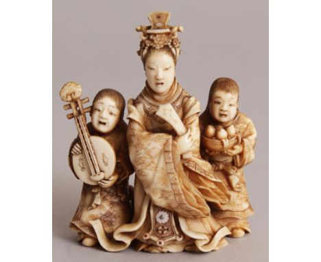 A FINE QUALITY SIGNED JAPANESE MEIJI PERIOD STAINED IVORY OKIMONO, of Kwannon bearing a tablet and flanked by two boy attenda