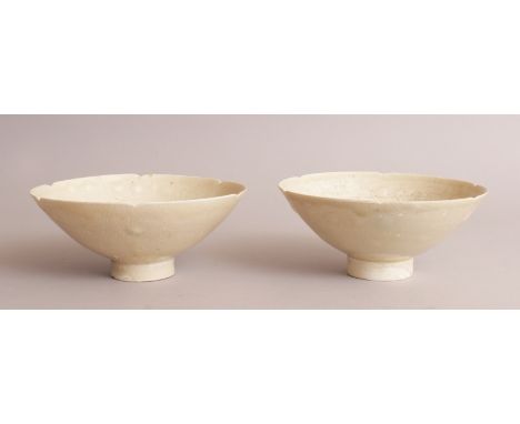 A PAIR OF CHINESE SONG DYNASTY DING WARE CERAMIC BOWLS, with indented rims, each interior incised beneath the celadon cream g