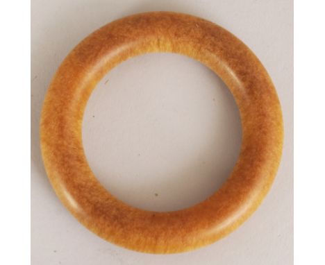 A HORN BANGLE, of yellowish-amber tone and with a tight grain, 3.5in diameter,the inner rim 2.25in diameter.