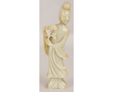 A GOOD 19TH CENTURY CHINESE CELADON JADE CARVING OF GUANYIN, standing in flowing robes and bearing a flower spray, the stone 