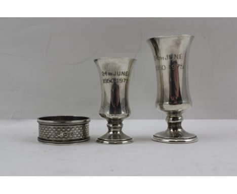 THREE PIECES OF HALLMARKED SILVER, being two tots and an engine chased napkin ring 