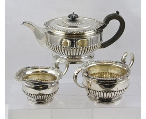 AN EARLY 20TH CENTURY THREE-PIECE SILVER TEA SET, of squat partially fluted form with scallop and gadrooned rims, comprising 