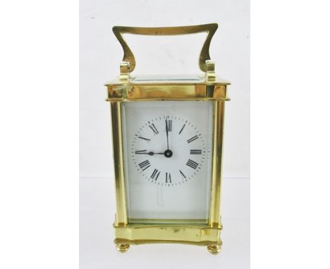 A 20TH CENTURY BRASS FRAMED CARRIAGE CLOCK having serpentine shaped case with bevelled glass panels, white enamel dial with R