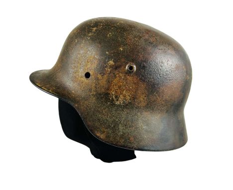 German M35 helmet used during World War II. The shell retains some of the original dark green camouflage paint, along with a 