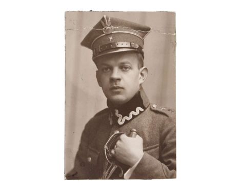 A portrait photograph of a second lieutenant in an officer's uniform wz.1927 and a wz.19 rogatywka (cap), holding a captured 