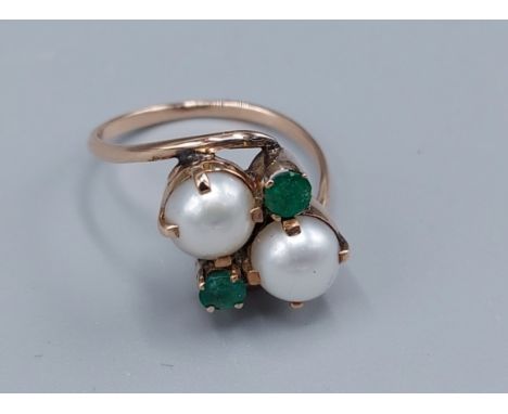 An unmarked tested gold cross-over ring set with two Pearls and two Emeralds, claw set, 2.8gms, ring size N