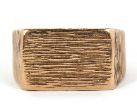 A 9ct ring, with 10mm wide textured plaque with tapered textured shoulders and plain lower band, hallmarked London 1974, size