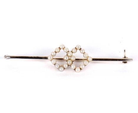 An 18ct seed pearl bar brooch, set to centre with two interlocked diamond shapes set with seed pearls, to plain white bar sta