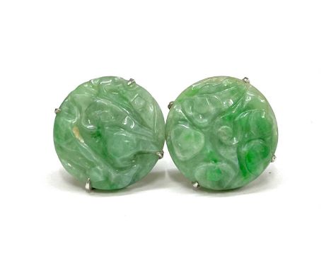 A pair of Jade earrings of circular form, carved with a foliate design. Four claw set in a precious metal mount stamped 9ct, 