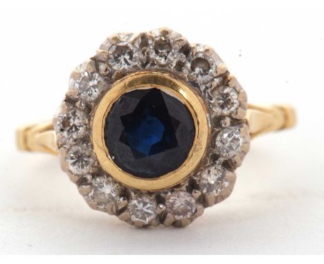 An 18ct sapphire and diamond ring, the central round sapphire in a rubover mount, surrounded by illusion set diamonds, with s