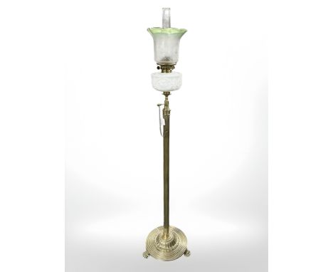 A late 19th century brass standard oil lamp on lion paw feet, with opaque moulded reservoir and etched two tone shade, height