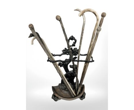 A Victorian painted cast iron stick stand containing rustic walking sticks 