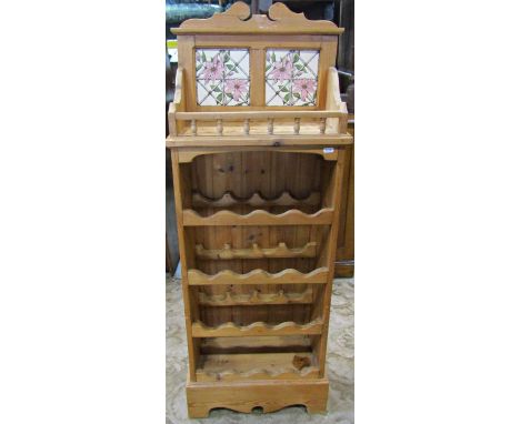 A stripped pine kitchen floorstanding wine rack to hold sixteen bottles, with galleried shelf and decorative floral tiled bac
