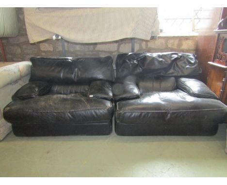 A pair of low substantial easy chairs with soft black leather upholstered finish and loose shaped feather filled cushions, 10