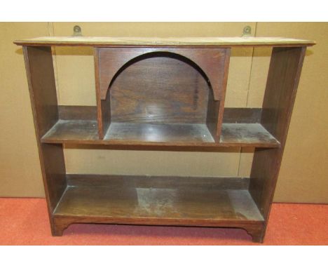 An arts and crafts oak wall mounted book shelf on two tiers with central arch, 60cm wide 