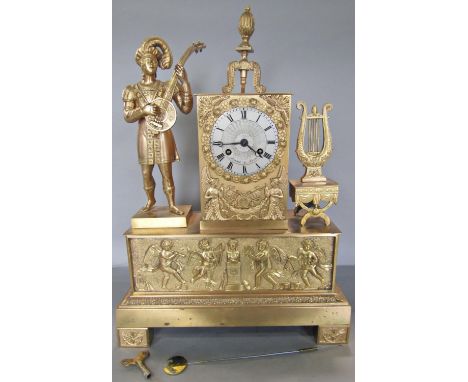A French Empire period gilt brass mantle clock with silvered dial and two train striking movement, flanked by a lyre musician