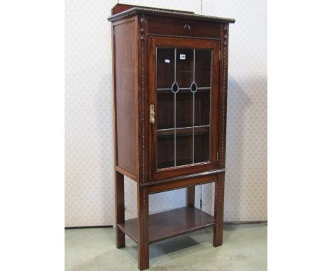 A 1920s Jacobean revival oak side cabinet enclosed by a rectangular leaded light panelled door, flanked by applied split moul