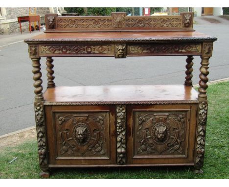 A Victorian carved oak buffet with lions mask, trailing fruit, vine, geometric and further detail, fitted with two well disgu