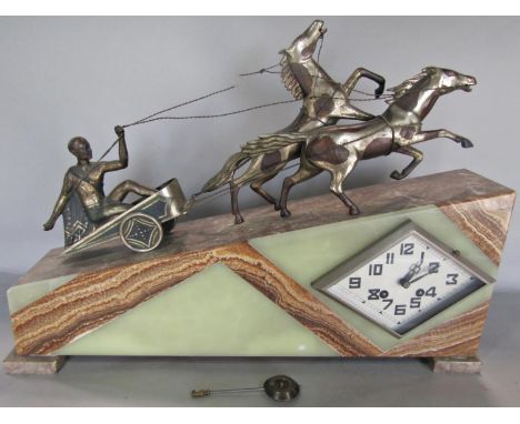 An art deco wedge shaped mantle clock, the casework in onyx and agate surmounted by a chariot pulled by two horses, the lozen