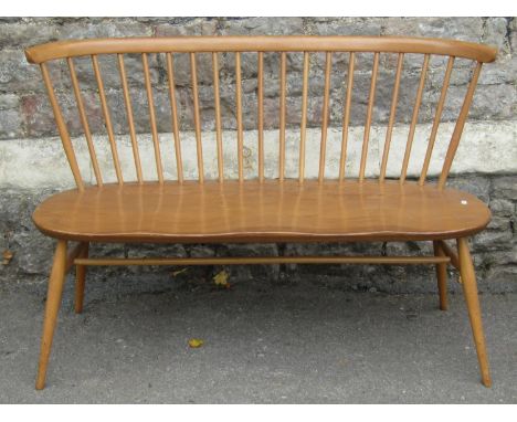 An Ercol light elm and beechwood loveseat/bench the raised simple stick back with curved moulded rail over a twin saddle shap