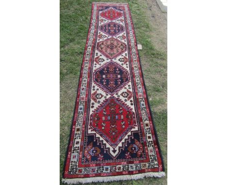 A Malayer runner with diamond shaped medallions with geometric patterns in blues and reds, 297cm x 83cm 