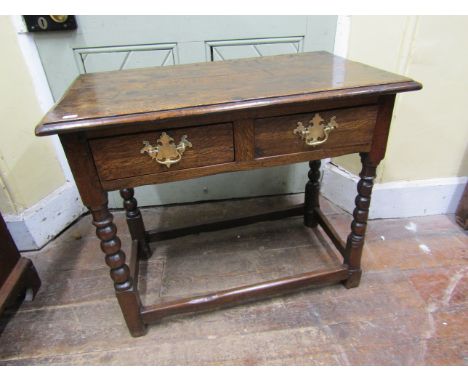 An antique oak side table enclosing two frieze drawers, raised on turned bobbin supports, 78cm wide