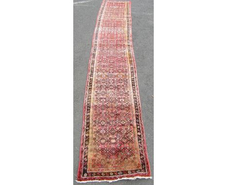 A Hamadan runner with a repeating geometric pattern on a predominantly pink ground, 500cm x 88cm. 
