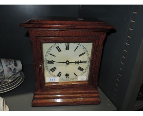A mid century enamel faced, oak bodied clock
