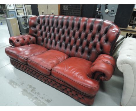 A red leather and button back sofa in a Chesterfield style