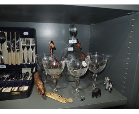 An etched glass decanter and glasses depicting various jungle wildlife and a selection of carved wooden animals