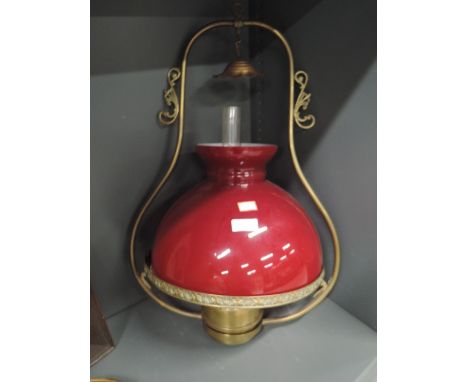 A ceiling mounted oil lamp with brass fitment and two tone red glass