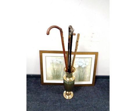 A brass embossed vase containing four assorted walking sticks, cane with silver pommel together with a pair of contemporary p