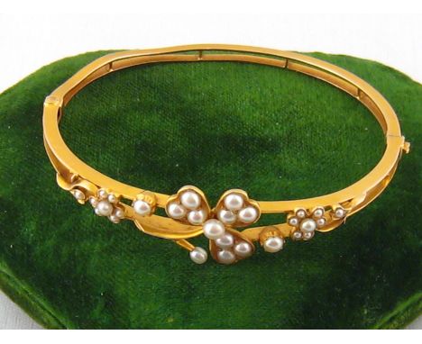 An antique 15 carat gold Art Nouveau seed pearl bracelet, the central floral motif approx 1.5cm wide, internal width approx 5