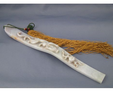 A Chinese jade sceptre carved in relief with a dragon chasing the flaming pearl, approx. 32 cm long, with silken tassel. Prov